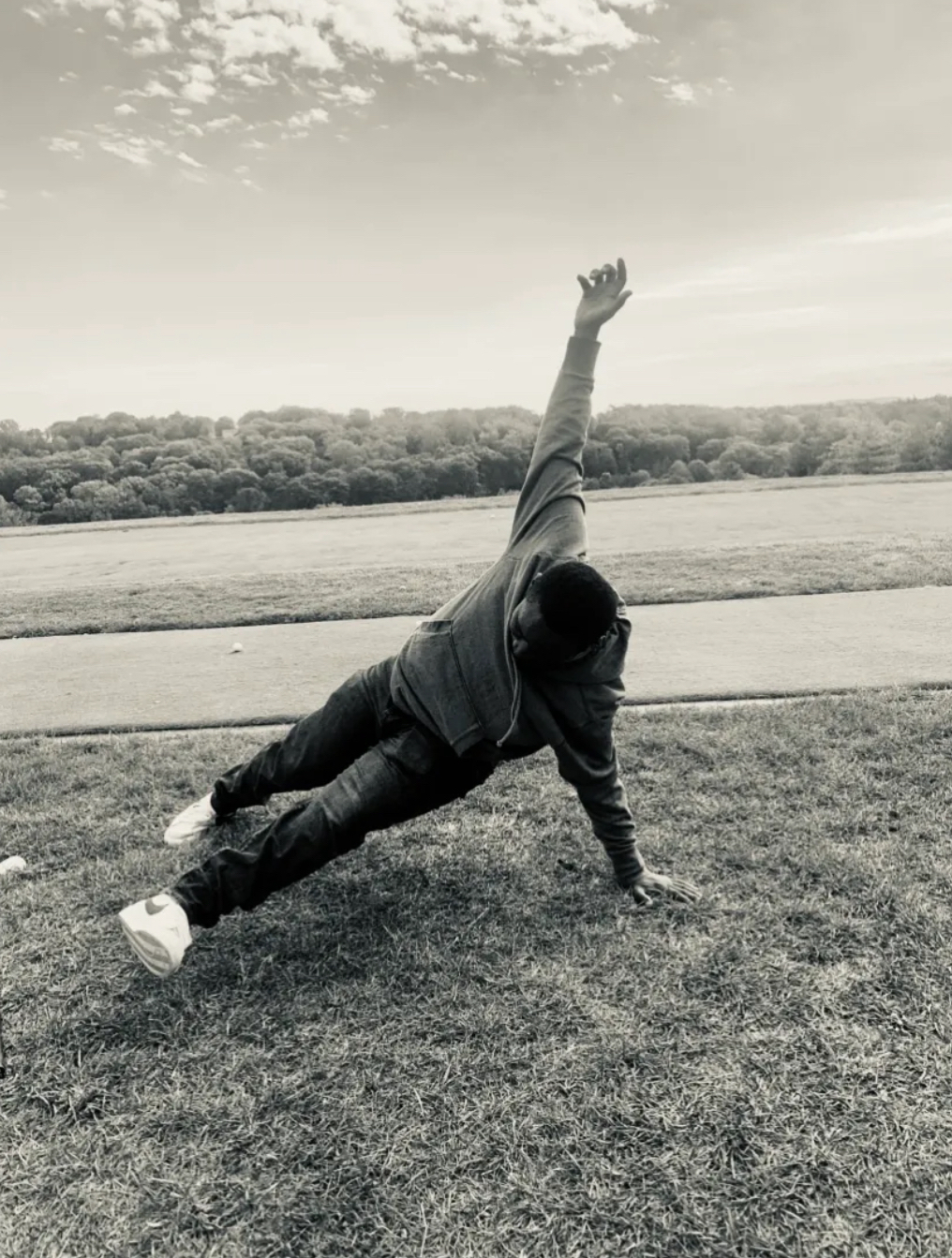 A student of Coach Bill's in an extended side-plank pose in an open field